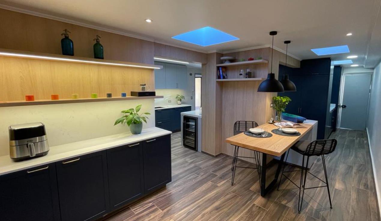 Cocina con muebles azul marino, lucarnas y comedor de diario en madera