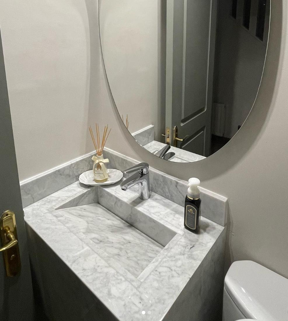 Baño de visitas con vanitorio de mármol de Carrara y espejo oval