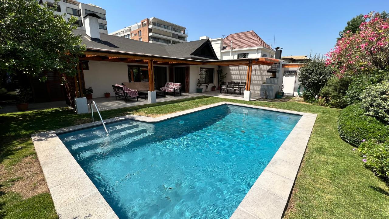 Piscina con solárium de piedra, pérgola de madera y terraza techada